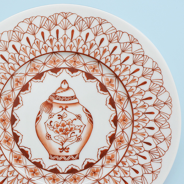 繊細な赤絵文様の真ん中に中国風の壺が描かれた丸皿の部分アップ