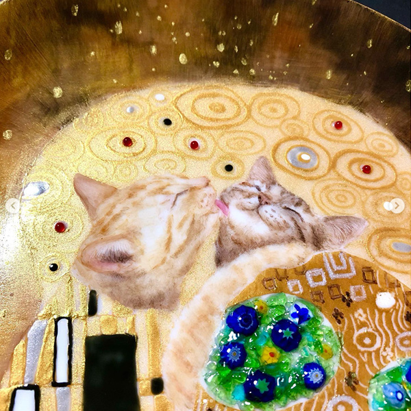 金やビーズで装飾した猫が描かれた丸皿の猫のアップ