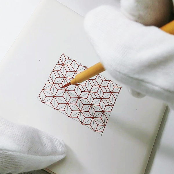 並べた細い筆と描きかけの赤絵の作品