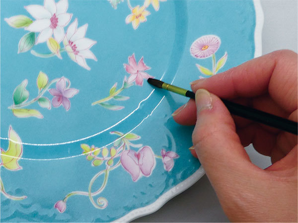 青いお皿に花を描いている手元