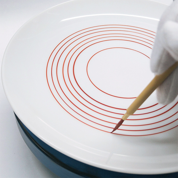 並べた細い筆と描きかけの赤絵の作品