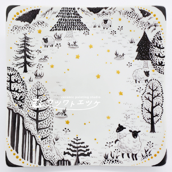 黒と金の絵具で木や羊や星が描かれた角皿